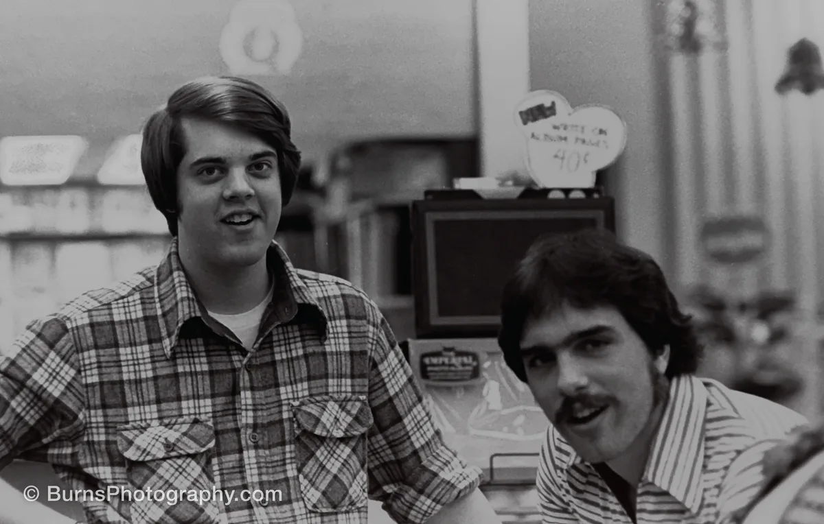 Black and white portrait of two young men working in a camera shop