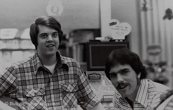 Black and white portrait of two young men working in a camera shop