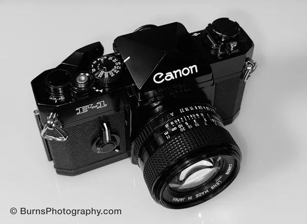 Black Canon F-1 35mm SLR with prime lens, shutter speed dial, f-stop and focus ring shown