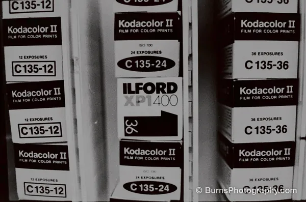 Stacked film boxes labeled Kodacolor II C135-12, C135-24, and C135-36, plus one Ilford XP1 400 box