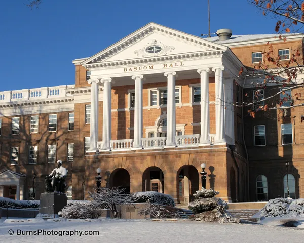 Bascom Hall's white columned portico and sandstone facade above a snow-covered hill with the seated Lincoln statue