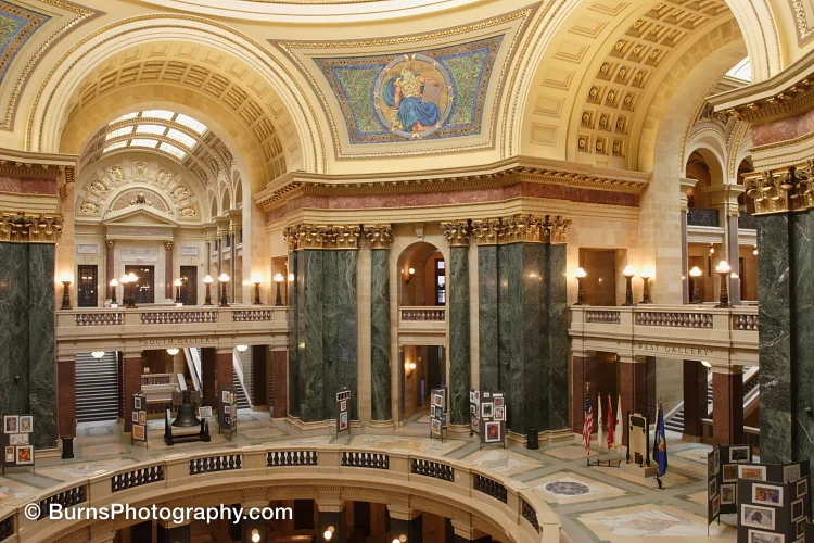 Interior of Wisconsin State Capitol rotunda with green marble columns, arched galleries, and a mosaic above