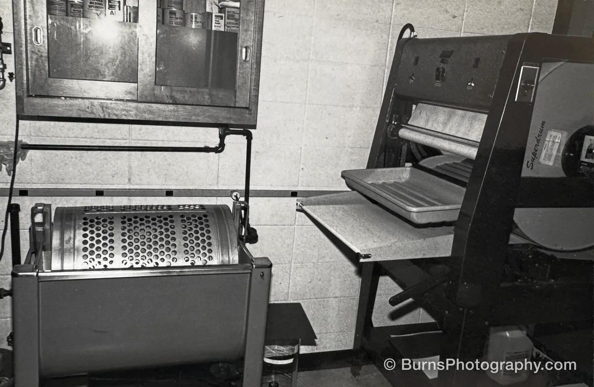 Darkroom interior with a rotary print washer, drum print dryer, tray, and wall cabinet