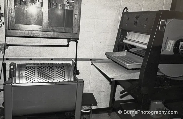 Darkroom interior with a rotary print washer, drum print dryer, tray, and wall cabinet